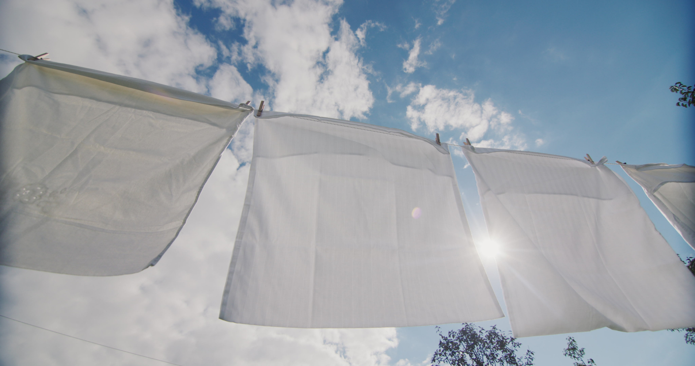 White bedding pillowcase linen sheets drying on a line in the sun bleach