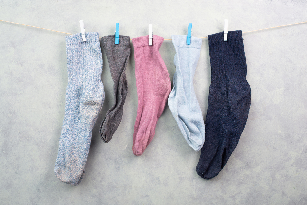 Single orphan lost socks hanging on a clothesline with a clothespin, missing sock after washing in the washing machine