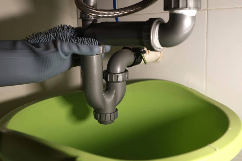 person cleaning the siphon of a sink