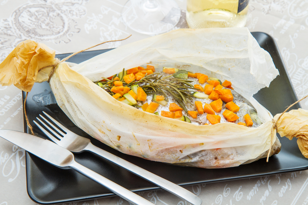 Sea bream baked in foil with vegetables cooking in foil against the smell of fish and bad kitchen odors