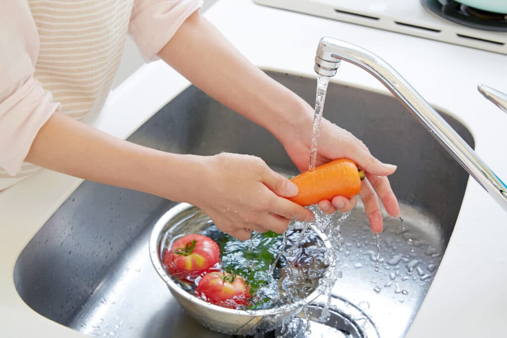 person washing vegetables in the sink 